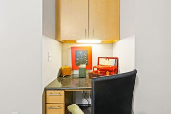built in computer niche with chair and cabinets above